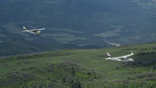 AX140_087E - 5.5K aerial stock footage of tracking Tecnam P2006T and Cessna aircraft over mountains and trees, Wasatch Range, Utah
