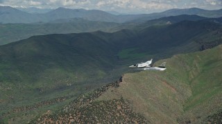 AX140_099E - 5.5K aerial stock footage of following a Tecnam P2006T over green mountains, Wasatch Range, Utah