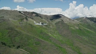 AX140_151E - 5.5K aerial stock footage fly beside a Tecnam P2006T passing green mountains, Wasatch Range, Utah