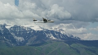 AX140_165E - 5.5K aerial stock footage of focusing on a  Tecnam P2006T passing by snow-capped Mount Timpanogos, Utah