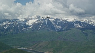 AX140_168 - 5.5K aerial stock footage of a Tecnam P2006T briefly flying by snow-capped Mount Timpanogos, Utah