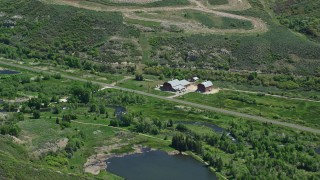 AX140_189E - 5.5K aerial stock footage of large barns near Old Highway 40 and a river, Heber City, Utah