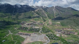 AX140_209 - 5.5K aerial stock footage of Canyons Resort, with view of snowy mountain peaks, Park City, Utah