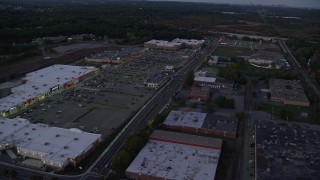 AX141_002 - 5.5K aerial stock footage flying by a strip mall, panning left, Westwood, Massachusetts, twilight
