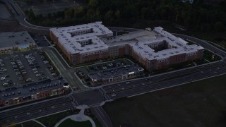 AX141_003 - 5.5K aerial stock footage flying by a large apartment building, Westwood, Massachusetts, twilight