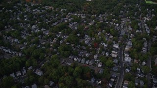 AX141_005E - 5.5K aerial stock footage flying over a suburban neighborhood, trees, Hyde Park, Massachusetts, twilight