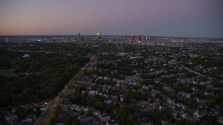 AX141_008E - 5.5K aerial stock footage of Blue Hill Avenue, approach downtown skyline, Dorchester, Downtown Boston, Massachusetts, autumn, twilight
