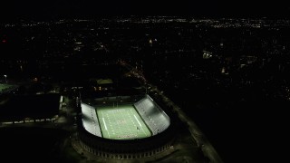 AX141_110 - 5.5K aerial stock footage flying by Harvard Stadium with the lights on, Harvard University, Massachusetts, night
