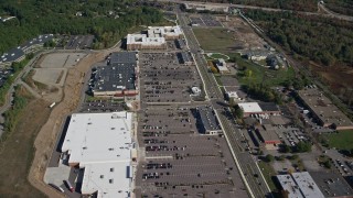 AX142_003E - 5.5K aerial stock footage flying over a strip mall bordered by trees in autumn, Westwood, Massachusetts