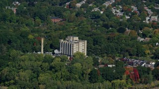 AX142_012 - 5.5K aerial stock footage flying by factory and smoke stack, trees in autumn, Hyde Park, Massachusetts