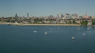 AX142_215 - 5.5K aerial stock footage flying by coastal community, anchored boats, skyline, South Boston, Massachusetts
