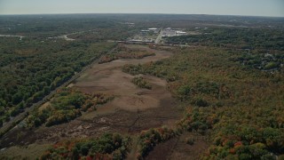 AX142_322 - 5.5K aerial stock footage flying over forest, approach warehouse buildings, autumn, Dedham, Massachusetts