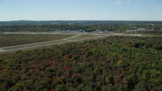 AX142_325 - 5.5K stock footage aerial video approaching and flying over airport in autumn, Norwood Memorial Airport, Massachusetts