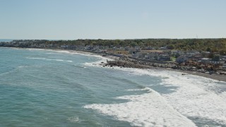 AX143_035E - 5.5K aerial stock footage flying by waves rolling onto beach, coastal community, Scituate, Massachusetts