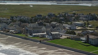 AX143_064E - 5.5K aerial stock footage approaching beachfront homes, rolling waves, beach, Duxbury, Massachusetts