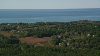 AX143_201 - 5.5K aerial stock footage flying by forest, homes with ocean views, Cape Cod, Truro, Massachusetts