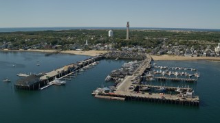 AX143_222E - 5.5K aerial stock footage flying by piers, small coastal town, Provincetown, Massachusetts