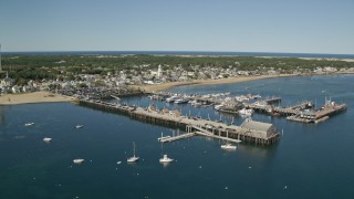 AX143_224E - 5.5K aerial stock footage orbiting piers, near small coastal town, Provincetown, Massachusetts