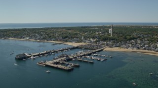 AX143_231E - 5.5K aerial stock footage orbiting small coastal town, piers, Provincetown, Massachusetts