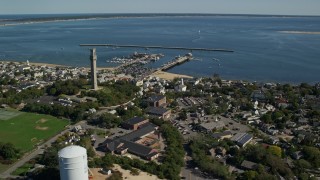 AX143_237E - 5.5K aerial stock footage orbiting small coastal town, Pilgrim Monument, piers, Provincetown, Massachusetts