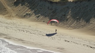 AX144_026 - 5.5K aerial stock footage flying by parachuter on the beach, Cape Cod, Wellfleet, Massachusetts