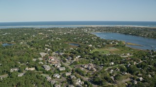 AX144_052E - 5.5K aerial stock footage flying by small coastal town, dense green trees, Chatham, Massachusetts