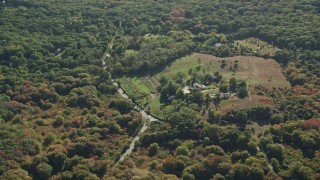 AX144_158 - 5.5K aerial stock footage flying by small farm, dense trees, Chilmark, Martha's Vineyard, Massachusetts