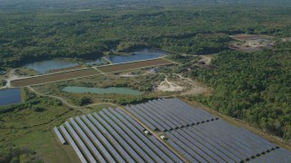 AX144_213 - 6k aerial stock footage flying by solar array, ponds, dense trees, Dartmouth, Massachusetts