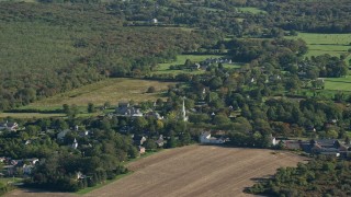 AX144_220 - 6k aerial stock footage flying by small rural town, dense green trees, Little Compton, Rhode Island