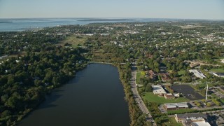 AX144_260E - 6k aerial stock footage approaching a coastal community, green trees, Newport, Rhode Island