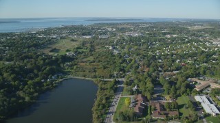 AX144_261 - 6k aerial stock footage flying over coastal community, dense green trees, Newport, Rhode Island