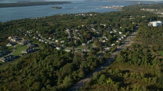 AX145_004 - 6k aerial stock footage flying over coastal homes, dense trees, lawns, Portsmouth, Rhode Island