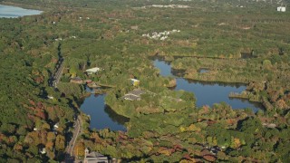 AX145_099 - 6k aerial stock footage flying by Orrs Pond, waterfront property, forest, autumn, Attleboro, Massachusetts