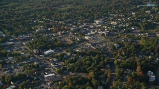 AX145_103E - 6k aerial stock footage flying by small town center, trees, autumn, North Attleborough, Massachusetts