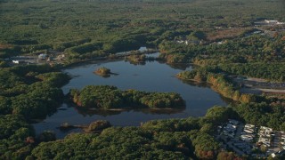 AX145_105 - 6k aerial stock footage flying by Turnpike Lake, green trees, autumn, Plainville, Massachusetts