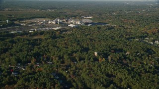 AX145_110 - 6k aerial stock footage flying by Gillette Stadium, dense trees, autumn, Foxborough, Massachusetts