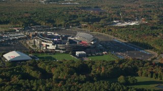 AX145_111 - 6k aerial stock footage flying away from Gillette Stadium, trees, autumn, Foxborough, Massachusetts