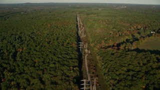 AX145_125E - 6k aerial stock footage flying by deciduous forest, power lines, autumn, Walpole, Massachusetts