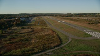 AX145_131E - 6k aerial stock footage flying by trees, autumn, approach the Norwood Memorial Airport, Massachusetts