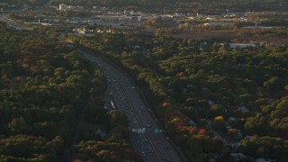 AX146_003E - 6k aerial stock footage flying by Interstate 93, heavy traffic, autumn, Westwood, Massachusetts, sunset