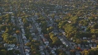 AX146_008 - 6k aerial stock footage flying by suburban neighborhood, autumn, Roslindale, Massachusetts, sunset