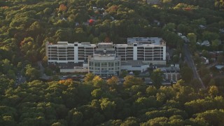 AX146_010E - 6k aerial stock footage flying by Faulkner Hospital in autumn, Jamaica Plain, Massachusetts, sunset
