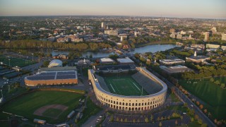 AX146_041 - 6k aerial stock footage approaching Harvard Stadium, Harvard University, Massachusetts, sunset