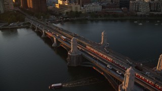 AX146_068E - 6k aerial stock footage tracking a commuter train across the Longfellow Bridge, Boston, Massachusetts, sunset