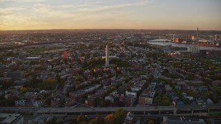 AX146_073E - 6k aerial stock footage flying by row house, Bunker Hill Monument, Charlestown, Massachusetts, sunset