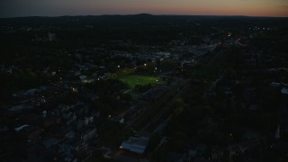 AX146_152 - 6k aerial stock footage flying by sports fields, tilt down, Jamaica Plain, Massachusetts, twilight
