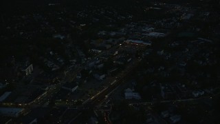 AX146_157E - 6k aerial stock footage flying over suburbs, approaching strip mall, Hyde Park, Massachusetts, night