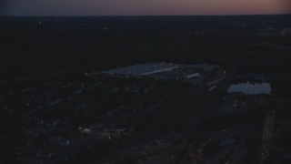 AX146_160 - 6k aerial stock footage flying by a large warehouse, Hyde Park, Massachusetts, night