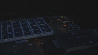 AX146_161 - 6k aerial stock footage flying by a large warehouse, Hyde Park, Massachusetts, night