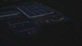AX146_162 - 6k aerial stock footage flying away from a large warehouse, Hyde Park, Massachusetts, night